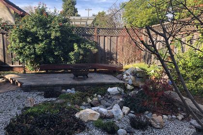 stone patio with fire pit, bench seating, and rock garden